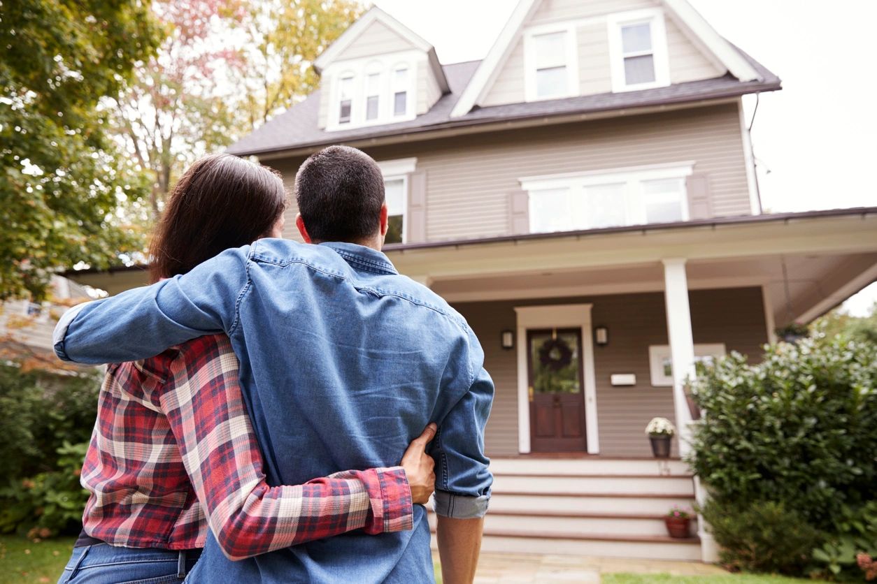 A man and woman standing in front of a house.