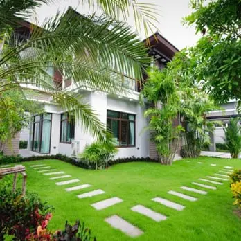 A large white house with palm trees and grass.